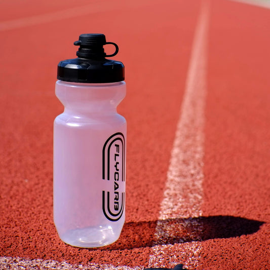 Clear water bottle with black lid on a red track